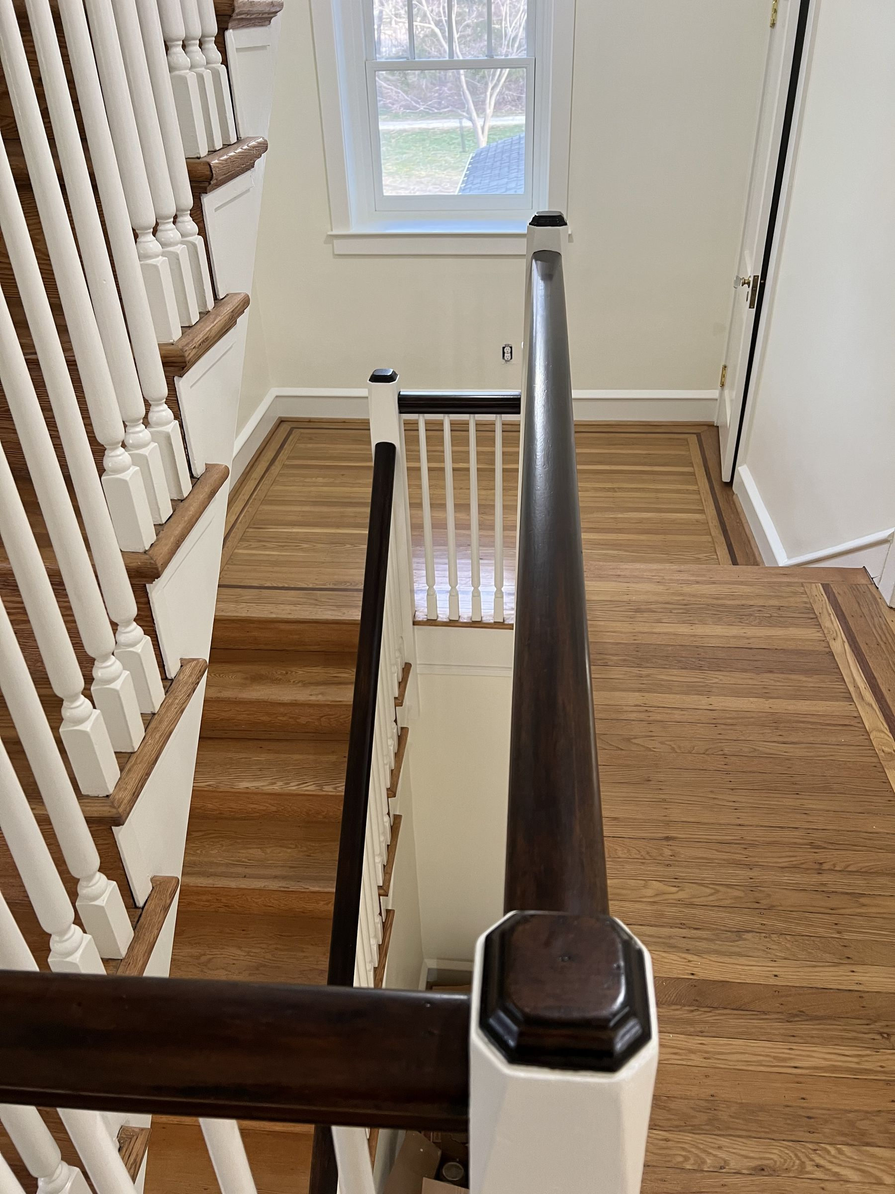 Freshly painted white stair balusters and risers with a dark stained handrail in a Philadelphia home